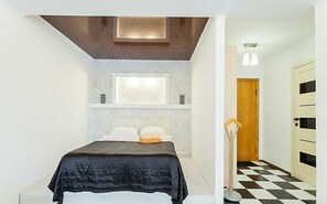 Relax in a serene bedroom with a large bed and a stylish wall-mounted shelf.