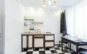 Cozy room with a kitchenette, dining area, and window with curtains.