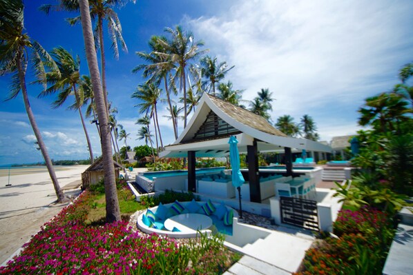 A resort with a pool area, palm trees, and a beach view.