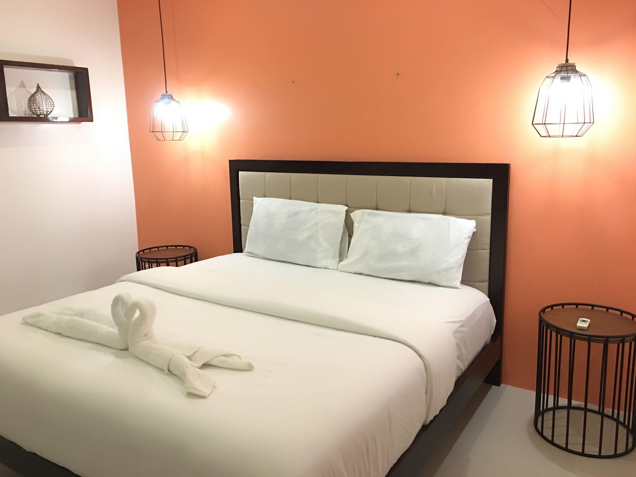 A neatly made bed with white linens and a towel, two bedside tables, and a headboard.