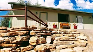 A rustic building with a wooden porch, a metal gate, and a stone wall in the foreground. - Mountain Views and Great Fire Pit (Star Valley)