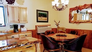 A dining area with a wooden table, leather chairs, a chandelier, and a deer figurine. - Mountain Views and Great Fire Pit (Star Valley)