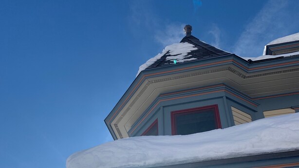 Un bâtiment recouvert de neige, avec des glaçons pendants du toit.