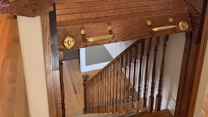 Un escalier en bois au design incurvé, une rampe en bois et, au fond, une vue sur un salon.