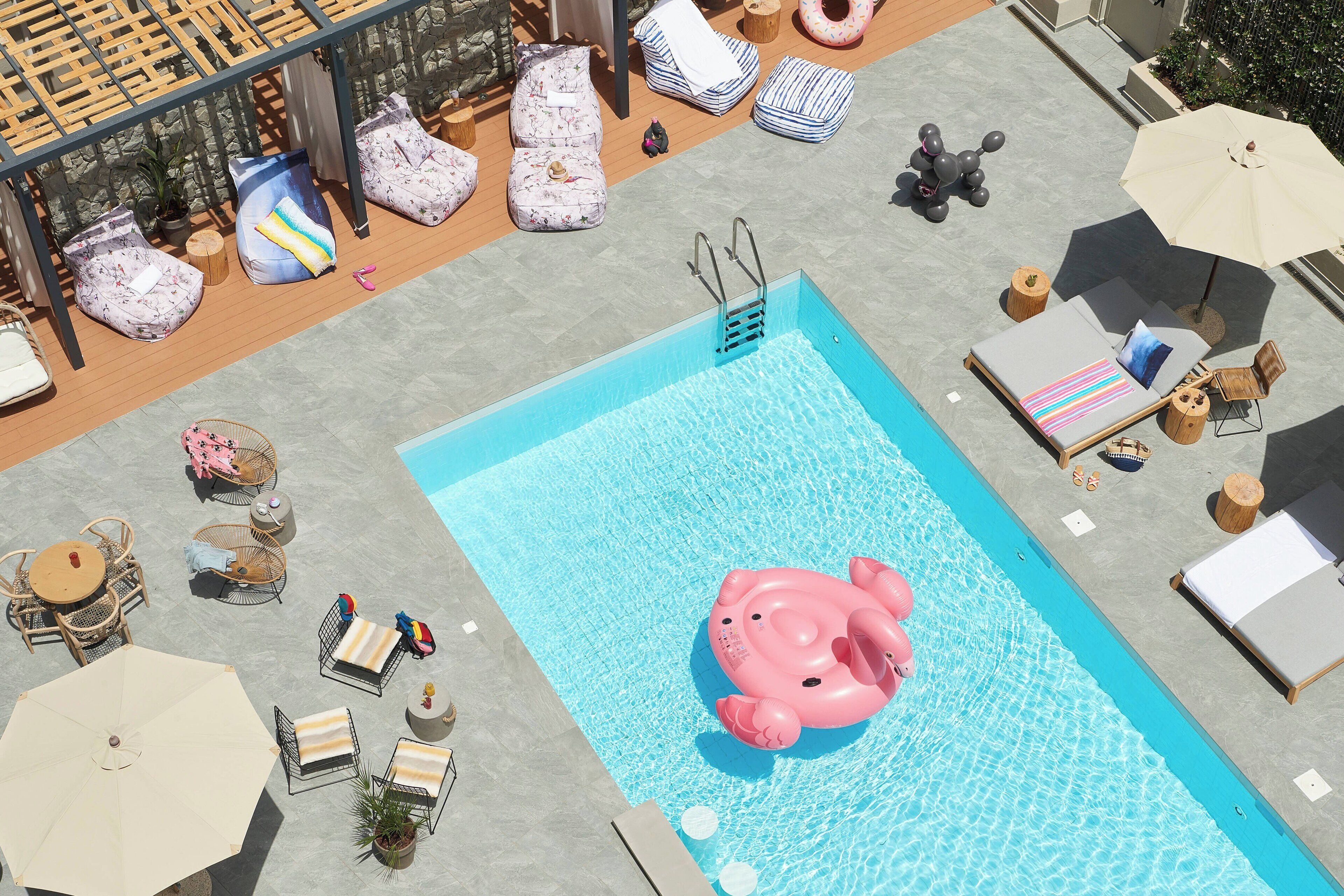 Un espace piscine avec des chaises longues, un flotteur rose et une terrasse en bois.