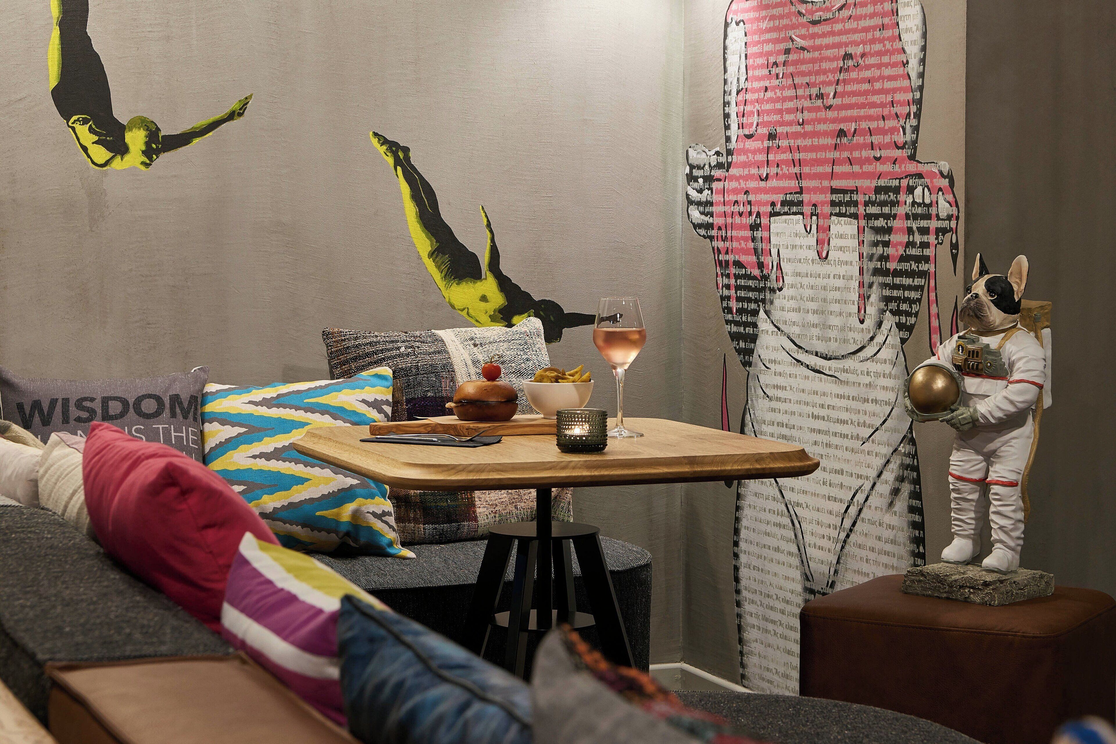 A cozy living room with a sofa, a small wooden table with a glass of wine, and a decorative astronaut figure.