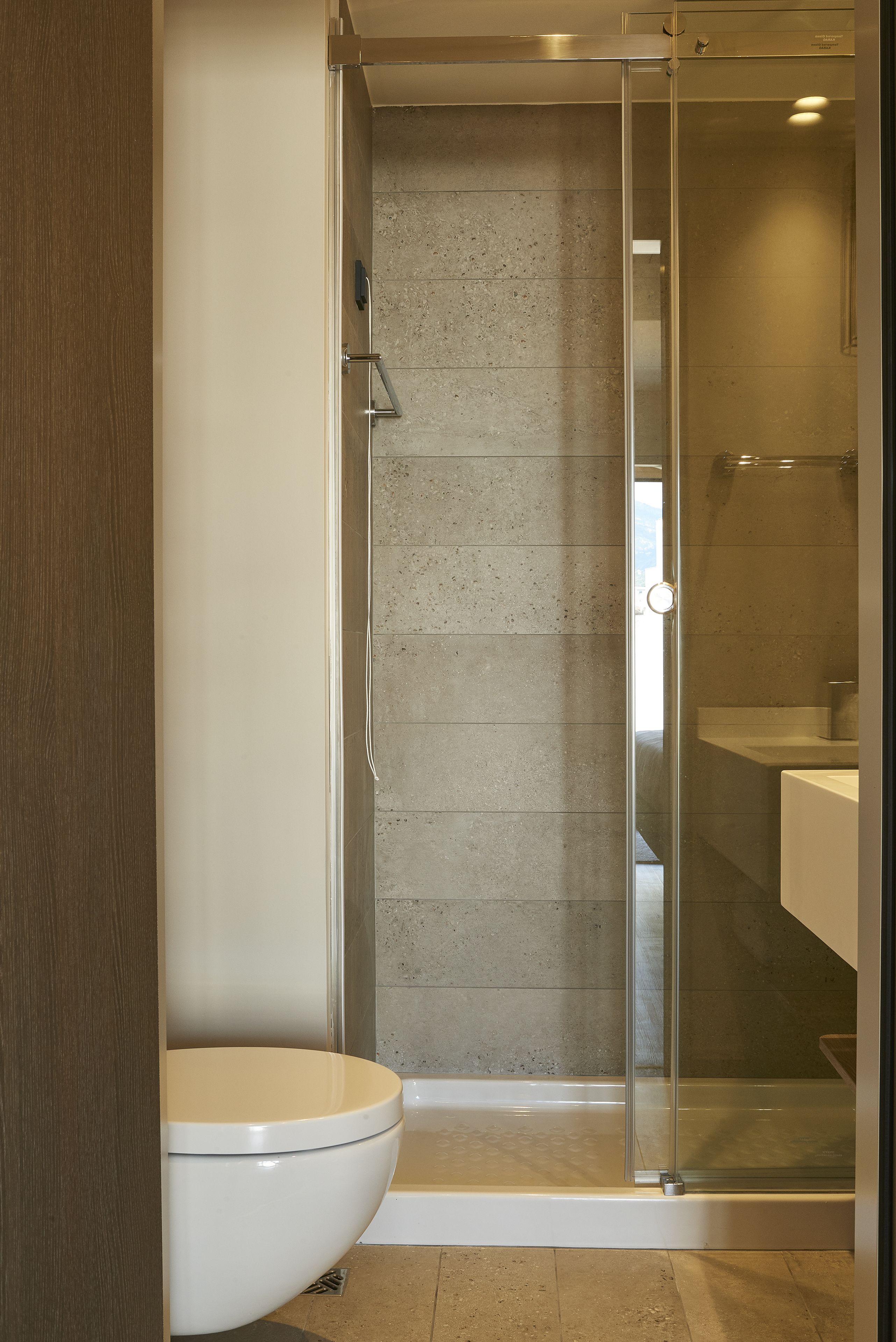 Un baño moderno con ducha acristalada, inodoro y lavamanos.