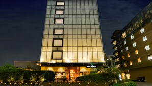 A tall hotel with a modern design, featuring a prominent entrance and a sign that reads "Citrus Patio". - Lemon Tree Hotel Viman Nagar Pune (Pune)