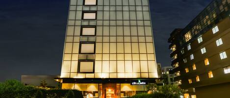 Un hotel alto de diseño moderno, con una entrada destacada y un letrero que dice "Citrus Patio".