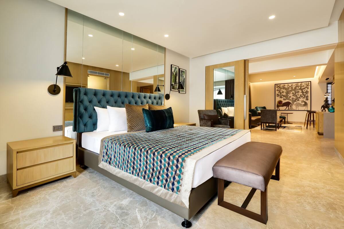 A modern bedroom with a large bed, bedside tables, a bench, a desk, and a chair.
