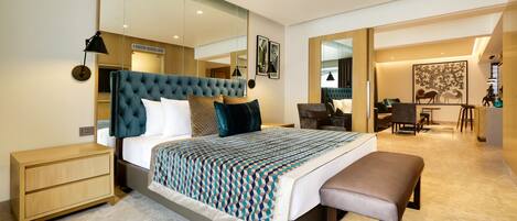 A modern bedroom with a large bed, bedside tables, a bench, a desk, and a chair.