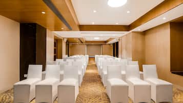 A conference room with rows of white chairs and a carpeted floor.