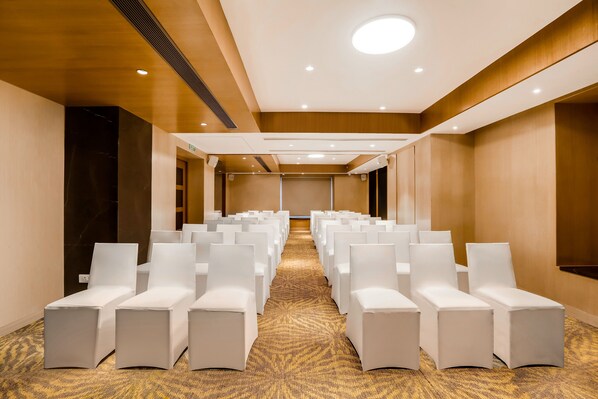 A conference room with rows of white chairs and a carpeted floor.