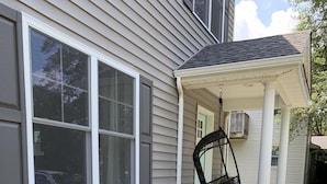 A house with a porch, a swing chair, and a garden with various plants and flowers. - PRICE REDUCED- includes linens and beach parking pass!  (Rehoboth Beach)