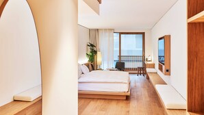 Una habitación de hotel moderna con una cama grande, un escritorio, una silla, un televisor y un balcón con vistas.