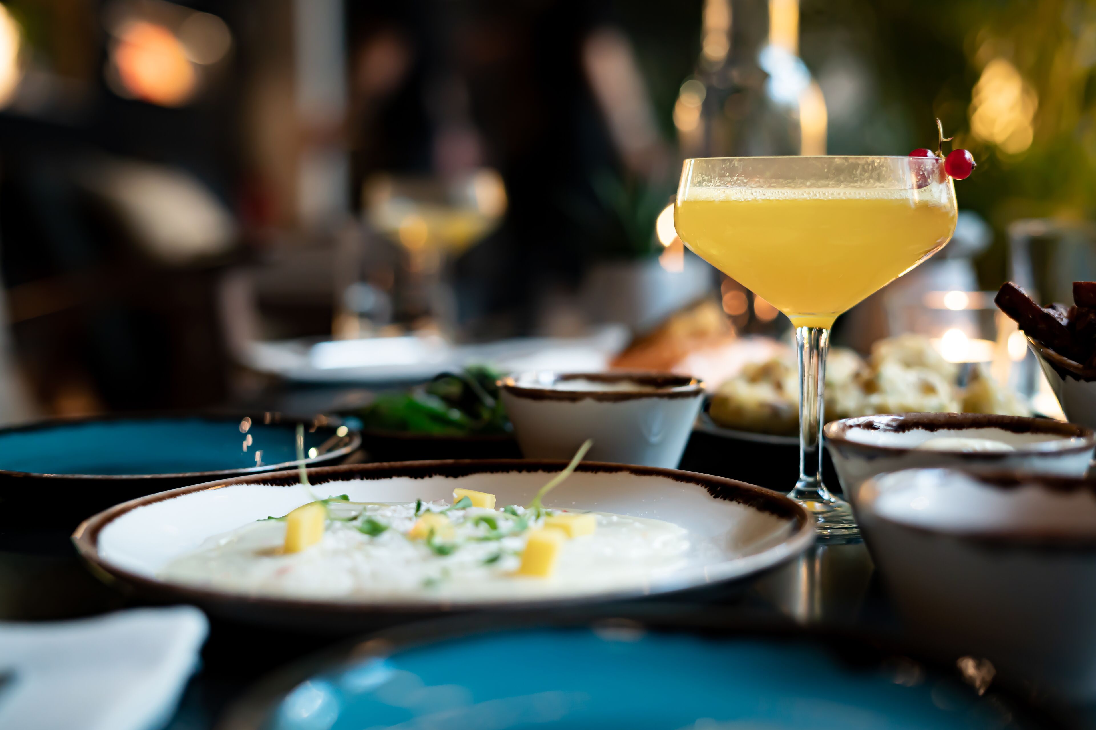 A table with various dishes, including a martini glass with a cherry garnish.