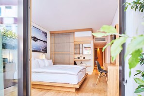 A modern bedroom with a wooden bed, a desk, and a large window.