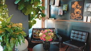 Un interior moderno con un sofá de cuero negro, una mesa redonda con un florero y una planta grande en maceta.