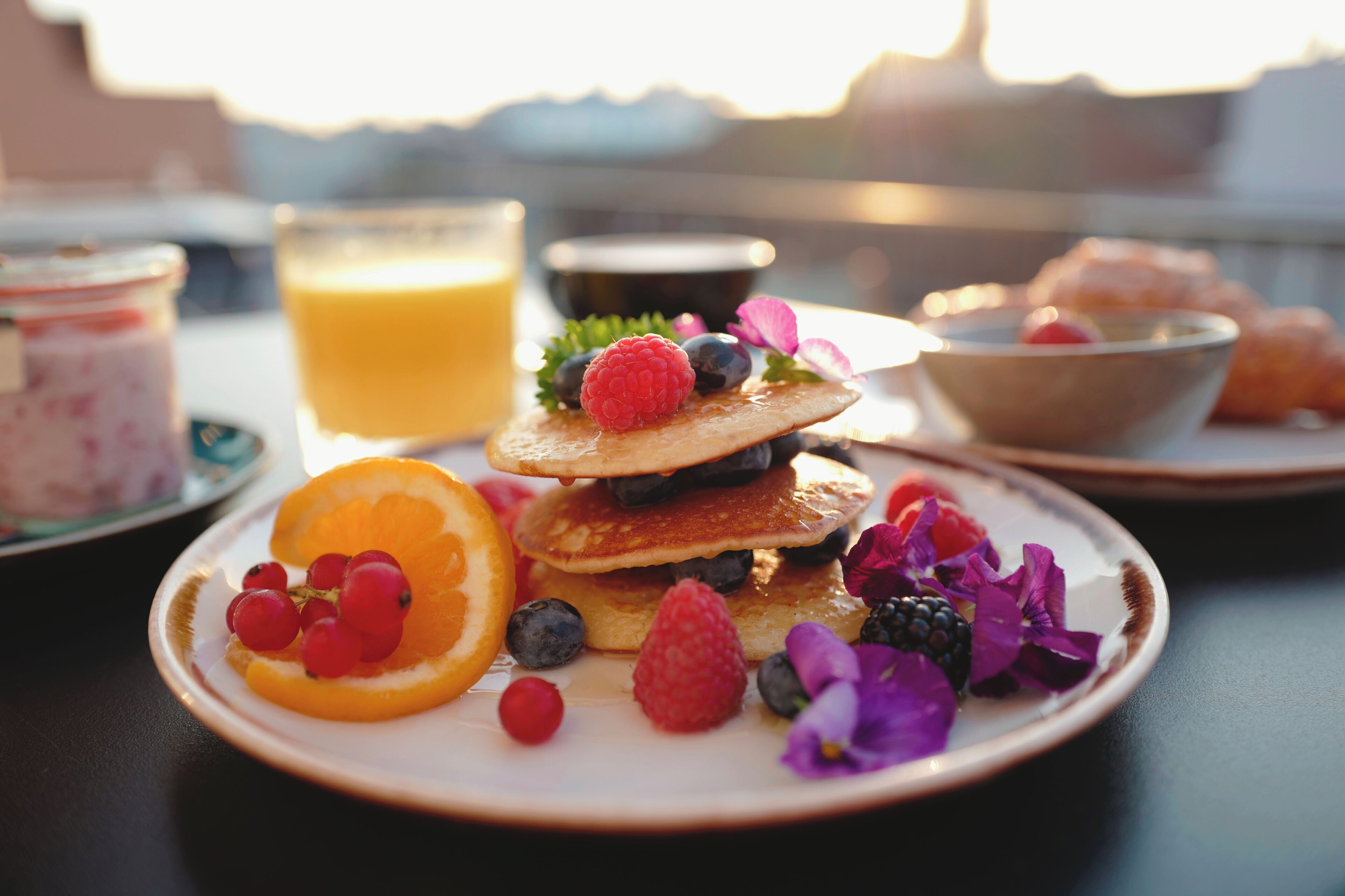 A breakfast plate with pancakes, berries, and orange slices.