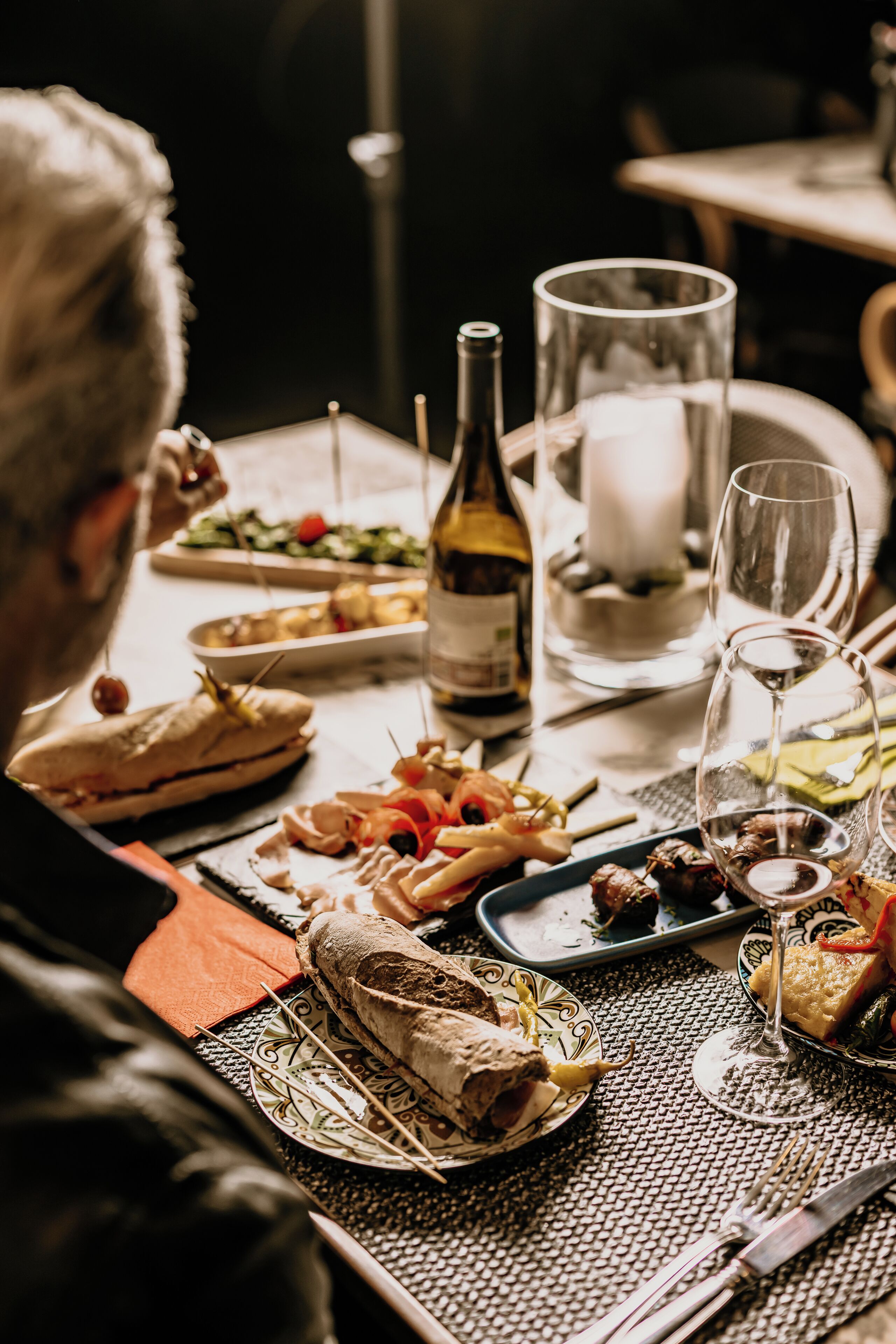 A dining table with various dishes, a bottle of wine, and a candle.