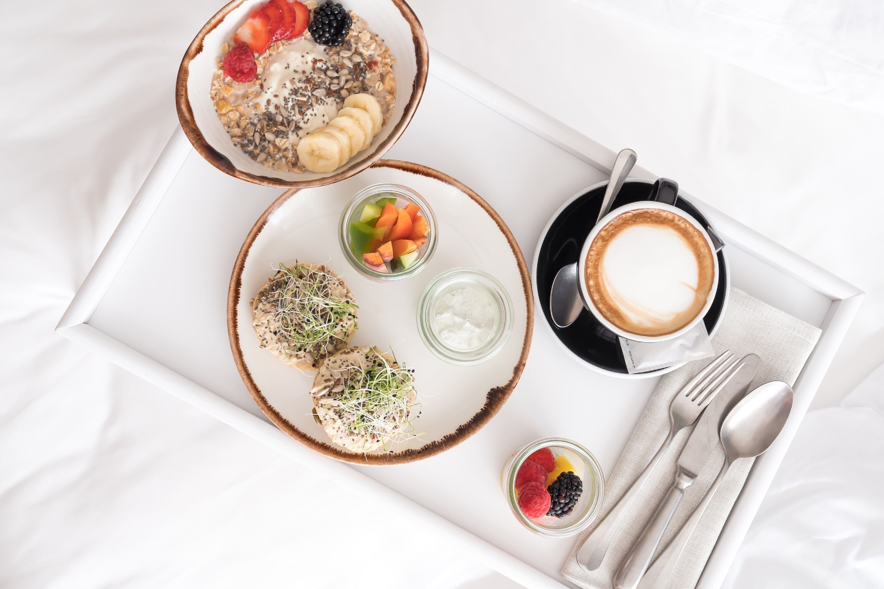 Un plateau de petit-déjeuner avec du porridge, du yaourt, des fruits et une tasse de café.
