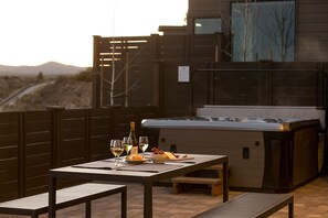 An outdoor dining area with a table set for two, a hot tub, and a view of the desert landscape. - RELAX! Soaking tub ~ fire place ~ hot tub ~ resort pool + amenities ~ Bend ~ 🐶 (Bend)