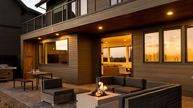 An outdoor patio with a fire pit, seating, and a view of the landscape.