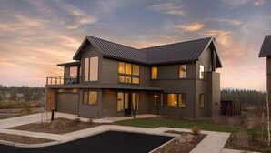 A modern two-story house with a large driveway and a landscaped front yard.