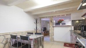 A dining area with a table and chairs, a stone wall, a kitchen area with a coffee machine, and a stone pillar.