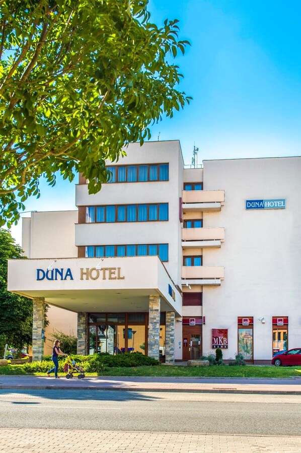 Um hotel com fachada moderna, entrada visível e placa indicando ser um hotel.