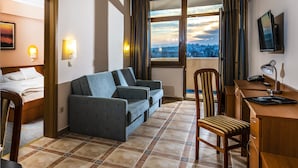 Une chambre d’hôtel équipée d’un canapé, d’un bureau, d’une chaise, d’un lit et offrant une vue sur le paysage urbain par la fenêtre.