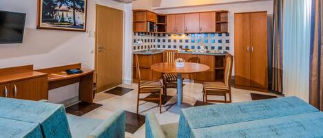 Cocina compacta con gabinetes de madera, salpicadero de azulejos y un comedor con mesa y sillas redondas.