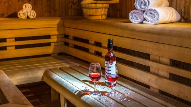 Un sauna en bois avec des bancs, des serviettes et une bouteille de vin.