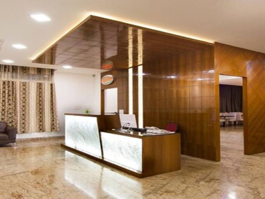 A modern reception area with a wooden reception desk, a sofa, and a staircase.