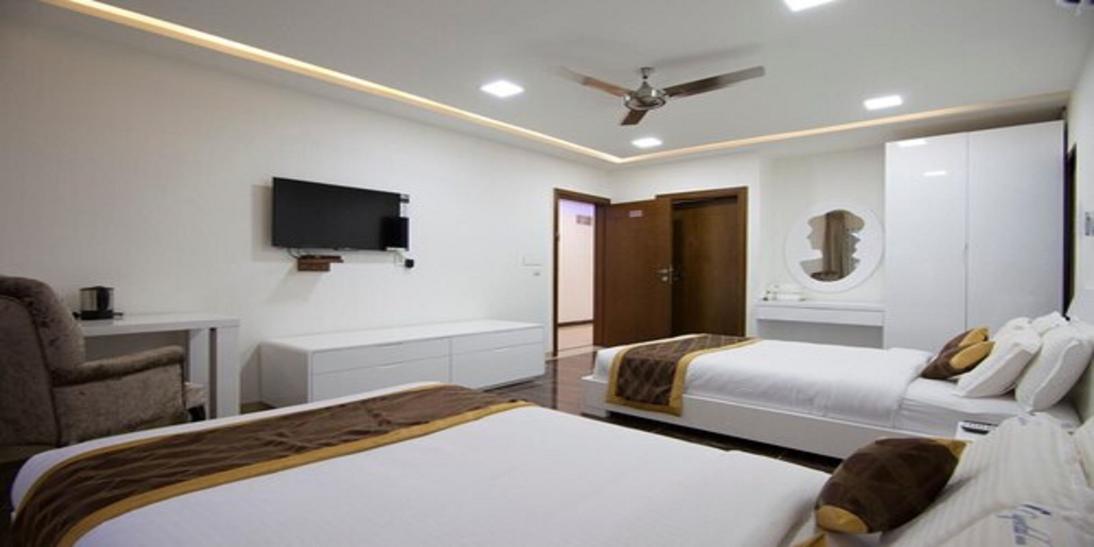 A hotel room with two beds, a TV, a desk, and a wardrobe.