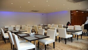 A conference room with white chairs and tables, equipped with nameplates and menus. - Crystal Inn (Chikkamagaluru)