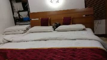Una cama con cabecera de madera, ropa de cama blanca y una manta roja.