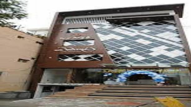 A building with a modern architectural design, featuring a prominent diamond-patterned facade and a staircase leading to the entrance. - Crystal Inn (Chikkamagaluru)