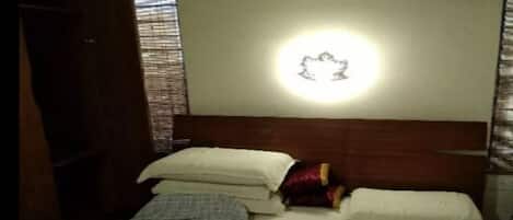 A bedroom with a bed, pillows, and a wall-mounted light fixture.