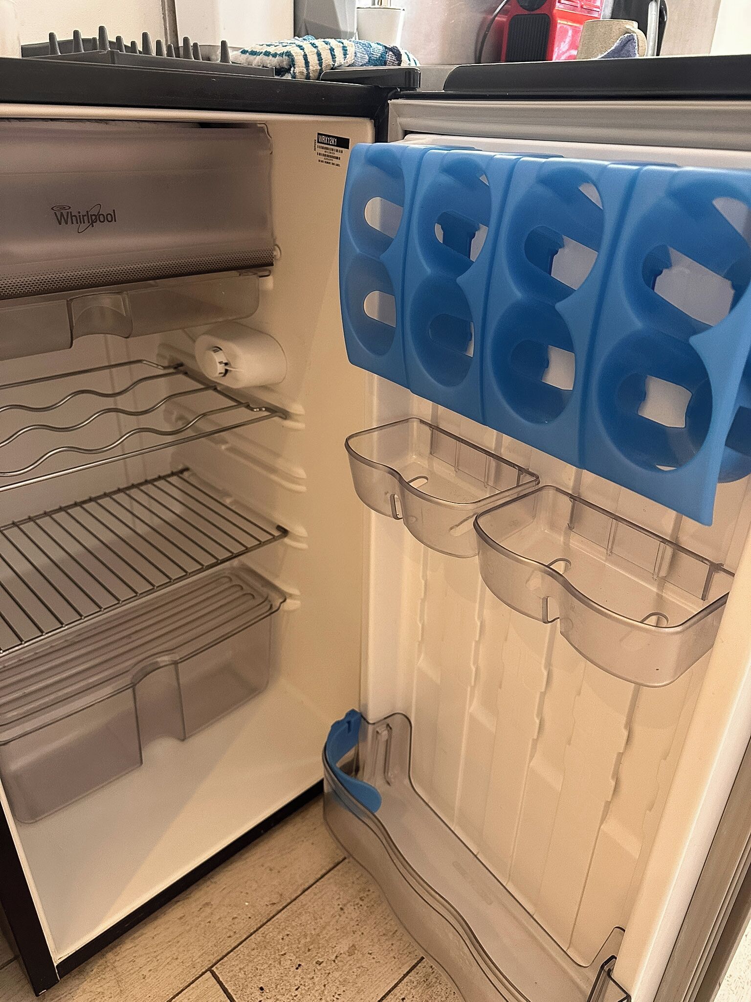 Uma geladeira aberta com um dispensador de gelo azul e um compartimento transparente para água e gelo.