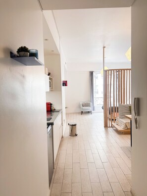 A modern kitchen with a built-in stove, a trash bin, and a dining area with a chair and a table.
