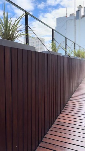 A modern outdoor staircase with a wooden railing and a metal handrail, leading to a higher level.