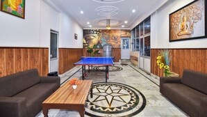 Een lobby met een tafeltennistafel, banken, een houten salontafel en een decoratief vloerpatroon.