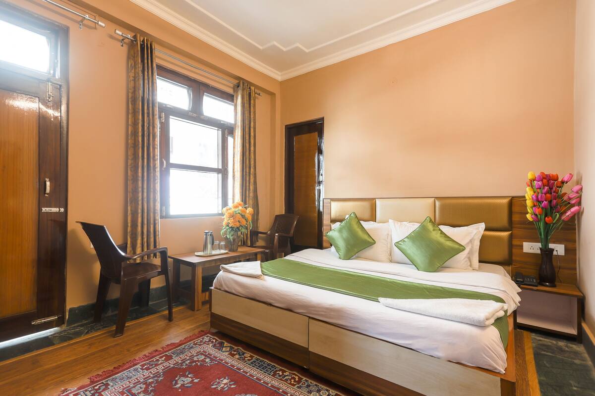 Une chambre d’hôtel avec un grand lit, un bureau, une chaise et une fenêtre avec des rideaux.