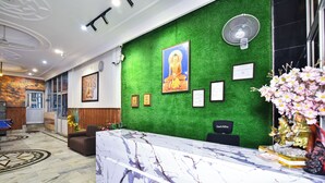 Een receptiezone met een groene wand, een marmeren balie en ingelijste certificaten.
