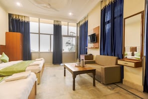 Una habitación de hotel con cama, sofá, mesita, televisor y espejo.