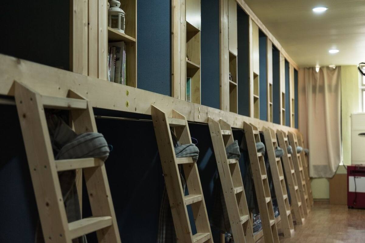 Une rangée d’échelles en bois appuyées contre un mur, avec des étagères au-dessus.