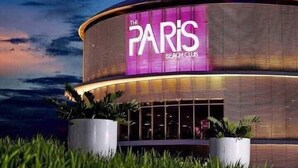 A modern building with a curved facade and a prominent illuminated sign reading "The Paris Beach Club".