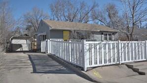 Uma casa residencial com garagem, cerca branca e calçada até a porta da frente.