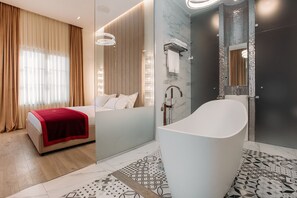 Una habitación de hotel moderna con una cama, una bañera grande y una zona de ducha.